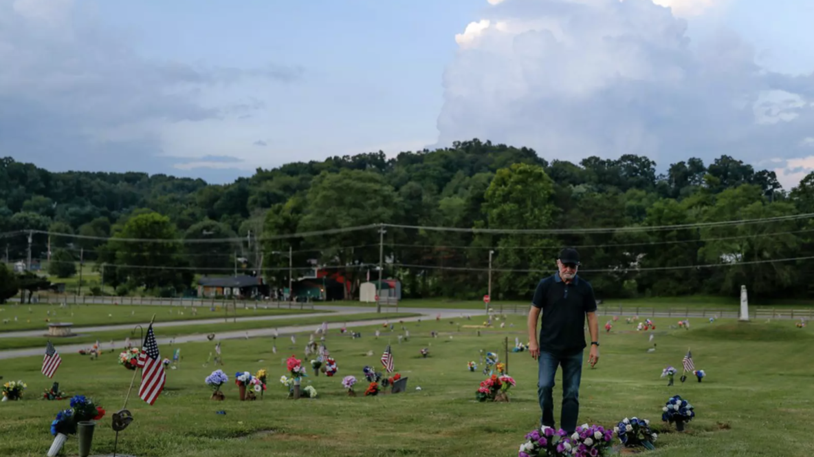 Man stands in cemetery with flowers